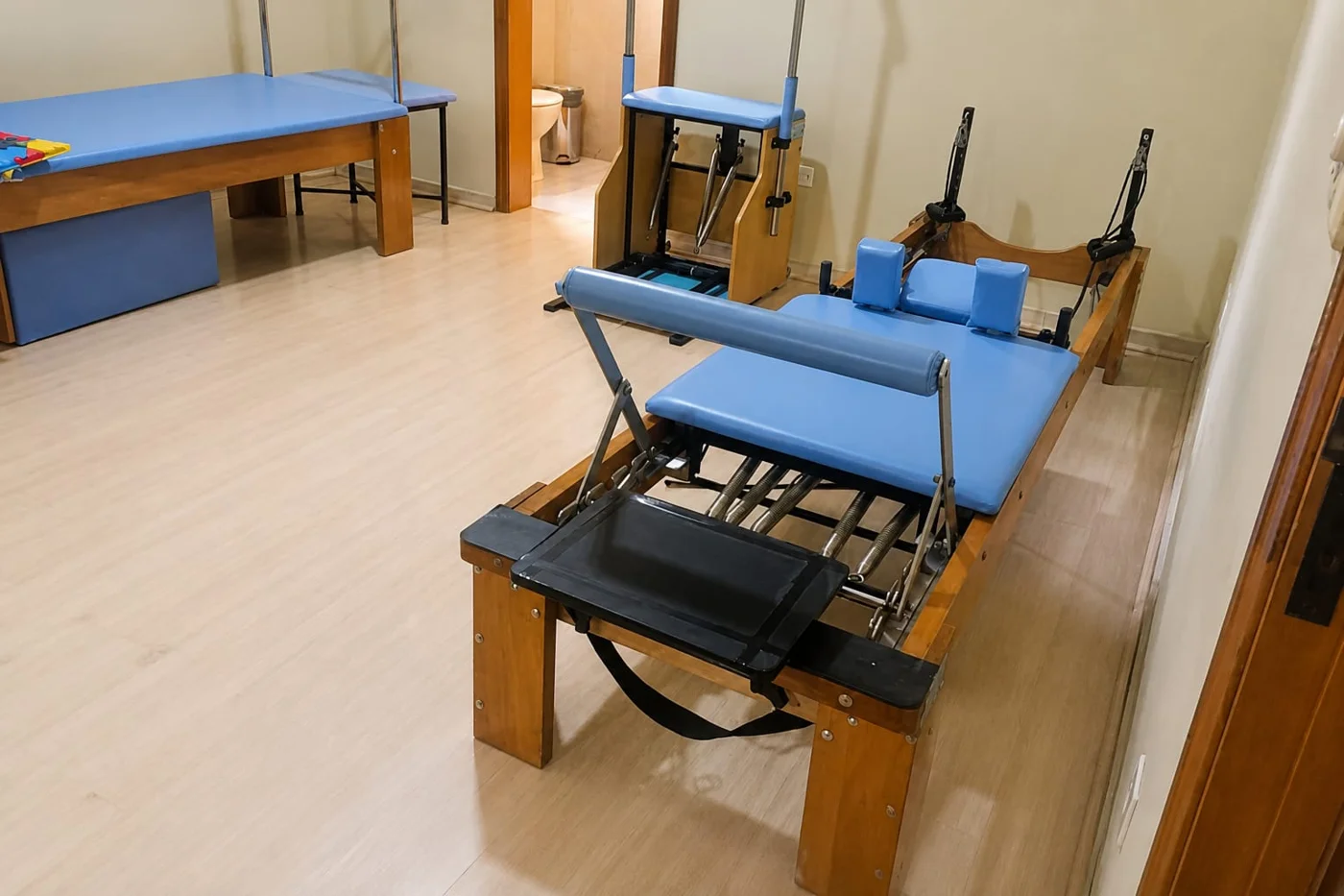 Sala de Pilates com aparelhos e piso de madeira